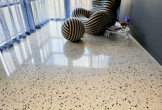 Salt and peppered polished concrete indoor flooring in an oval shaped picture.