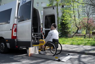 a man in a wheelchair wheel chair in front of a NEMT van