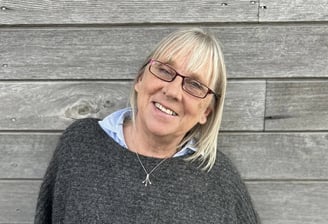 a woman in a gray sweater and glasses