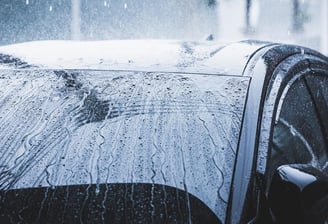 automobilis, kurio priekinis stiklas uždengtas lietumi, bet vanduo varva žemyn dėl hidrofobikos