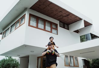 a happy father and child standing in front of a luxury house