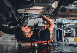 A man working under a car in a garage.