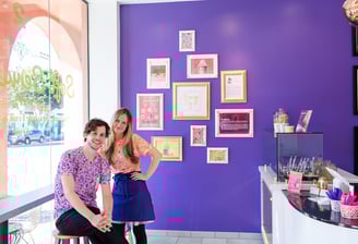 a man and woman standing in front of a purple wall