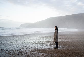 a woman standing on a beach with a mountain in the background