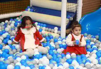 two young girls in red and white dresses playing in a ball pit in gurugram trumpy softplay