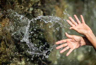 a person's hands are outstretched out of focus as they are touching the water