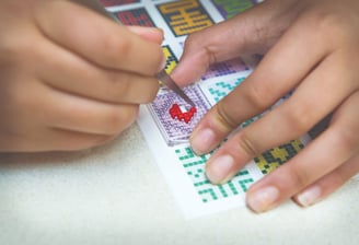 Human creating a picture by using tweezers, transparent baseplate and colorful pixel squares