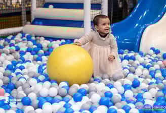 a baby girl in a ball pit with a ball in the middle of a ball