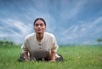 a woman doing Yoga on a grassy field