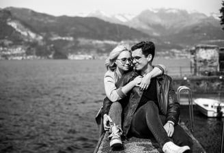 a couple sitting on a ledge overlooking the water