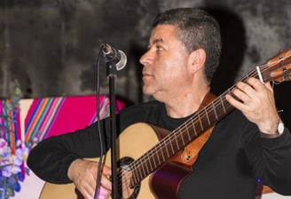 a man in a black shirt playing guitar and singing
