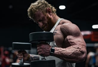 Muscular man lifting heavy dumbbells in a gym