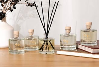 a table with a collection of home scents in glass bottles