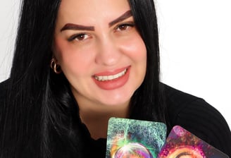 Gabriela Luna, terapeuta espiritual hispana, sonriendo mientras sostiene un tarot Rider-Waite y un c