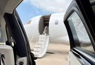 a car with a door open and a plane parked in front of it