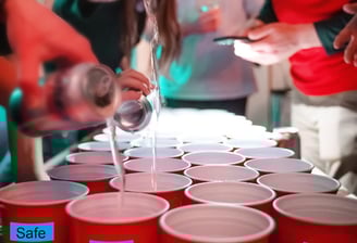 a man is pouring water into cups of red cups