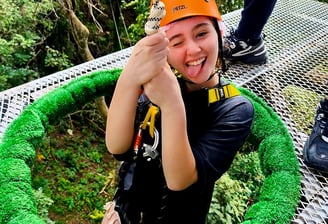 a woman in a helmet and helmet on a rope - zipline adventure park koh samui