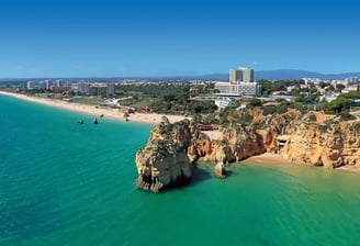 Golden cliffs and turquoise sea of Praia dos Três Irmãos and Praia do Alvor in Algarve, Portugal.