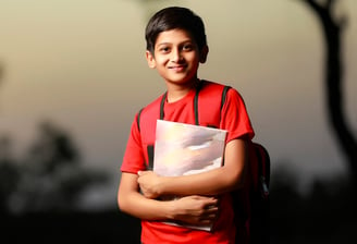 a young hindu student is holding a book and smiling