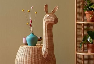 a wicker chair with a vase of flowers in a room