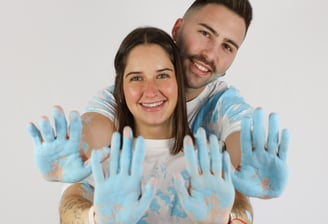 Sessió de fotos de gender reveal a Girona d'una parella amb pintura blava en estudi fotogràfic