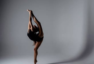 A young gymnast performing a balance with the leg lifted.