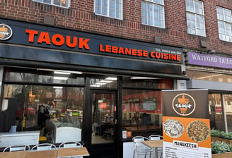 Taouk Watford restaurant logo displayed on a sign outside the building in Watford.