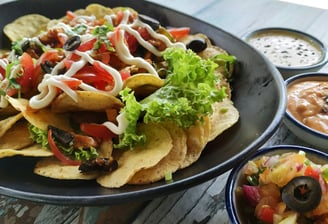 A taco on a black plate with visible fillings and sauces, neatly arranged with some spilling out.