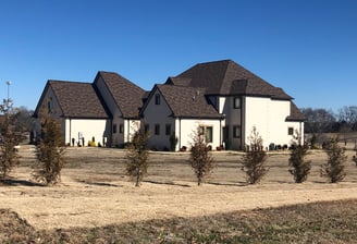 A new home designed by Veteto Design | Newly constructed large home with a blue sky and small trees