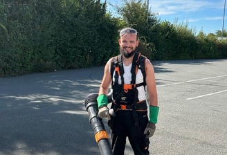 a man in a vest and a backpacker in a parking lot