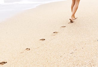 Voetafdrukken in zand op het strand bij de kustlijn.