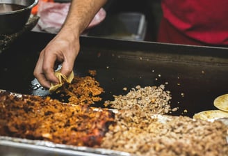 a person is cooking food in a pan on a grill, Street Local at Tacos Mixes Los Angeles
