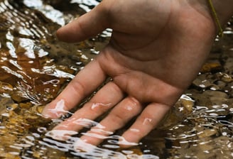Main dans l’eau claire symbolisant l’apaisement mental et la lecture subtile du champ énergétique