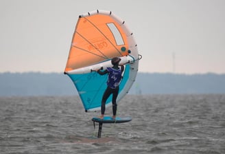 Mokytojas rodo pagrindinius wing foil valdymo principus ant kranto