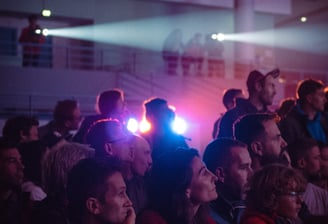 Public captivé devant une projection, éclairé par des faisceaux lumineux en ambiance immersive
