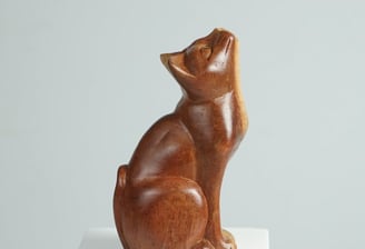 a wooden cat statue of a cat sitting sculpture on a pedestal
