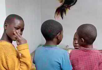 Image of 4 children in front of bird mural, with one looking back at the camera.