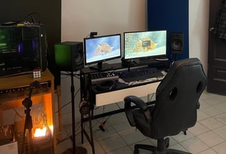 a man sitting at a desk with two monitors and a laptop