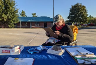 Person in a wheelchair filling out a survey at a table stationed to conduct surveys