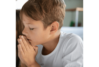 a young boy praying with his eyes closed