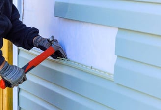 Man replacing siding on a home