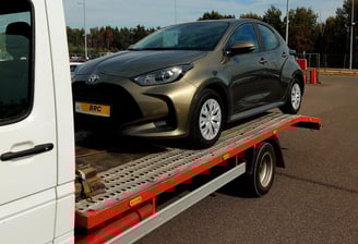 Skubios traliuko paslaugos pervežant automobilį kelyje.