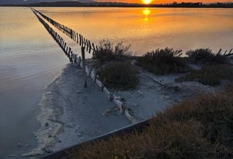 Sunset over the Molentargius wetlands in Cagliari, Sardinia, with a wooden barrier