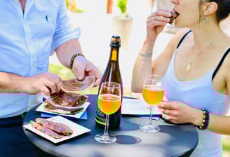 Couple qui déguste des galettes avec du cidre sur une table à l'extérieur