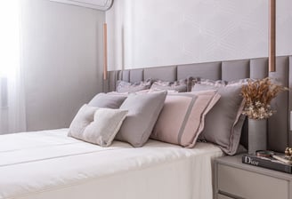 Quarto sofisticado com tons neutros e rosados, iluminação pendente elegante e detalhes que garantem aconchego e requinte.