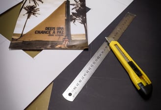 Uma fotográfia sobre uma cartolina e uma régua e um estilete sobre um papel preto