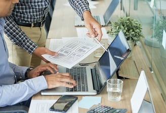 Deux hommes travaillant sur des ordinateurs portables dans une salle de réunion.