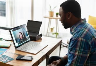 a man sitting at a desk with a laptop and a cell phone