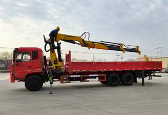 Yellow Zorylift SQZ350A.4 16T knuckle boom crane on red truck operated by worker. Heavy duty, truck/lorry mounted.