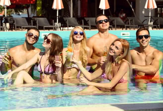 Group of friends enjoying drinks in a pool, representing the fun and social vibe of both private and public Vegas crawls.
